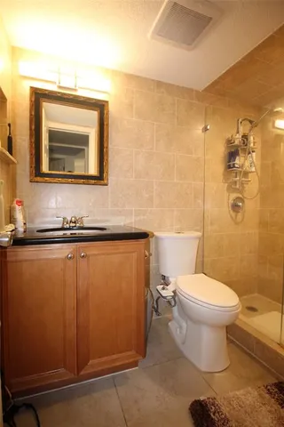 a bathroom with a granite countertop toilet sink and mirror