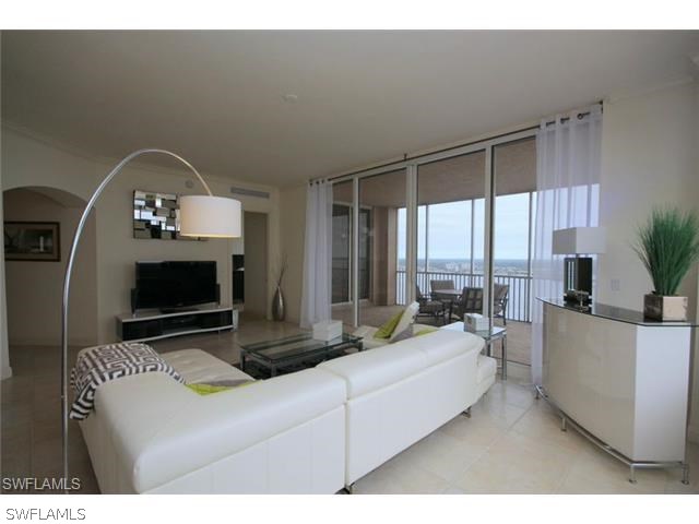 a living room with furniture a flat screen tv and a large window