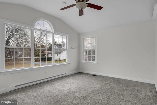 an empty room with windows and ceiling fan