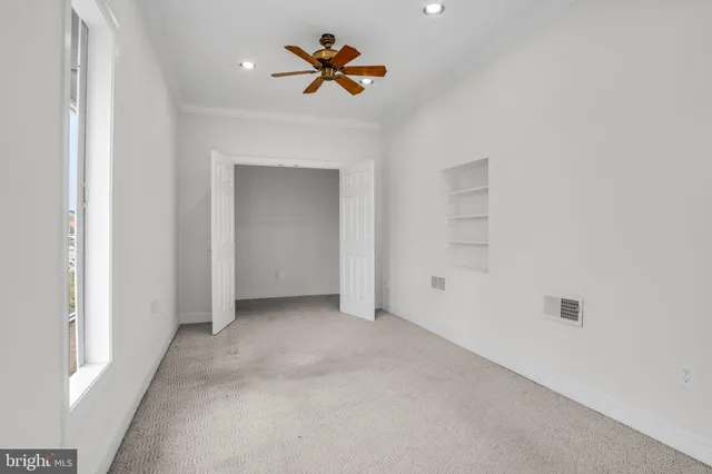 an empty room with closet and a ceiling fan