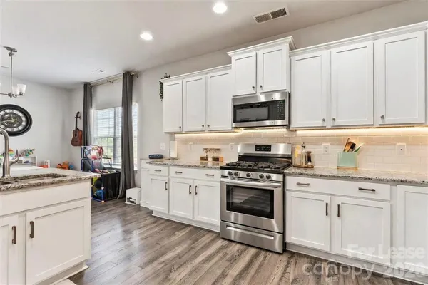 a kitchen with stainless steel appliances granite countertop a stove and white cabinets