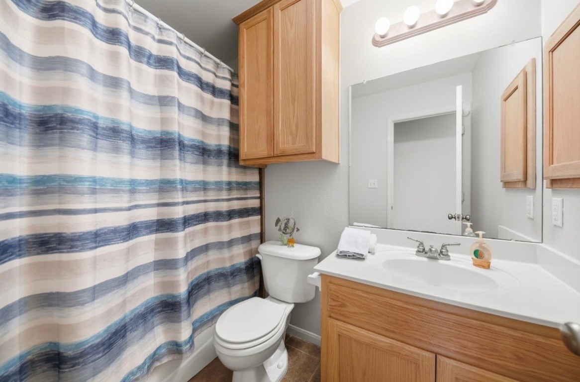306 Matula Avenue Schulenburg, TX 78956 - Photo 15 of 21 a bathroom with a sink a toilet a mirror and shower curtain