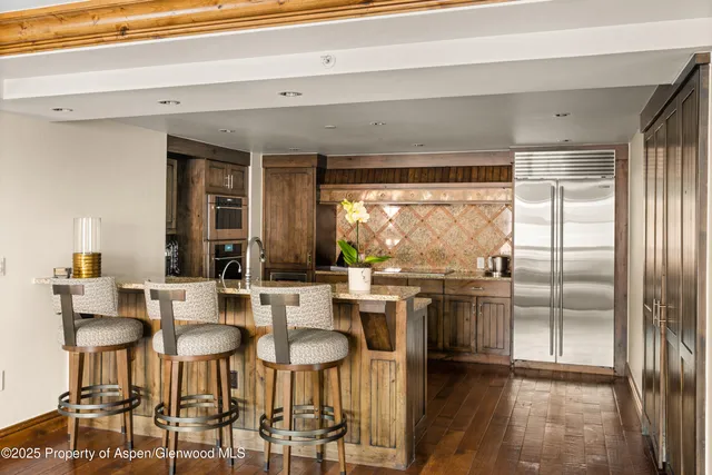 a kitchen with stainless steel appliances a dining table chairs and a refrigerator