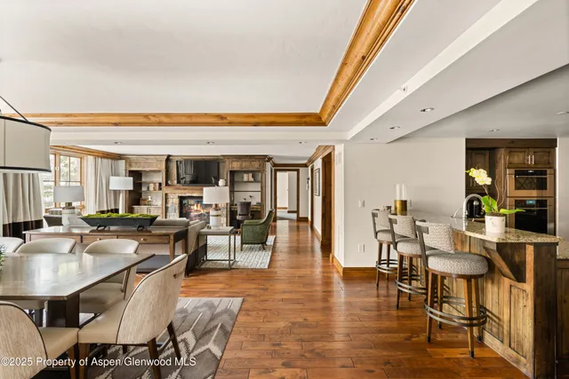 a dining hall with stainless steel appliances granite countertop a table and chairs with wooden floor