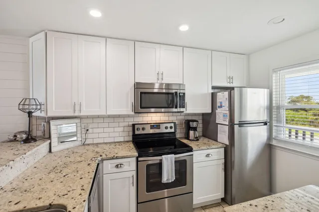 a kitchen with stainless steel appliances granite countertop a stove top oven a sink and white cabinets