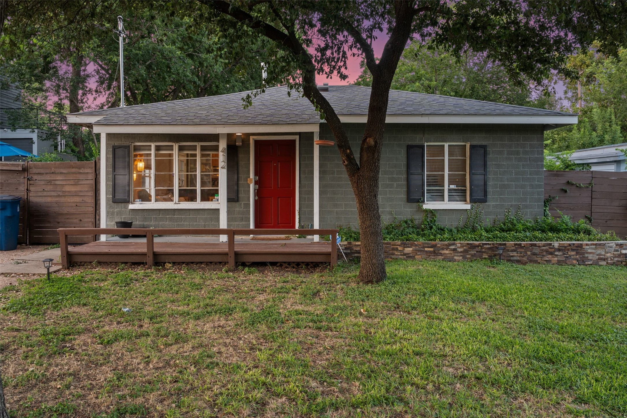 412 West Croslin Street Austin, TX 78752 - Photo 2 of 36 A charming bungalow with a vibrant red door, inviting deck, and well-maintained yard.