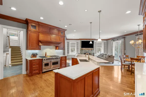 a kitchen with stainless steel appliances granite countertop a stove top oven a sink dishwasher a dining table and chairs with wooden floor
