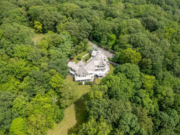 an aerial view of residential house with outdoor space and trees all around