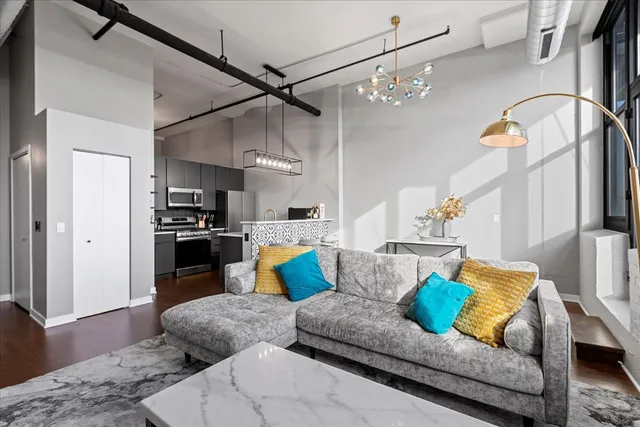 a living room with furniture kitchen view and a chandelier