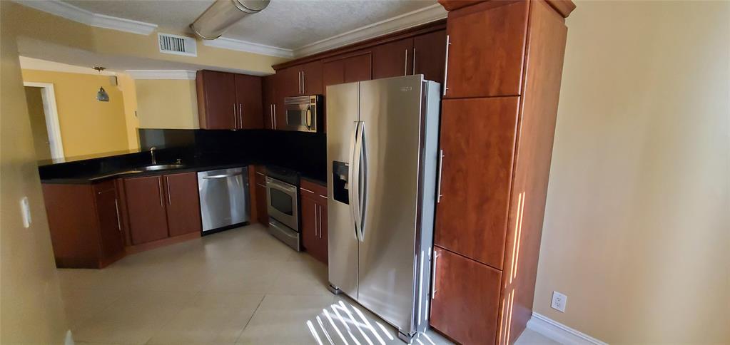 8781 Wiles Road, Unit 202 Coral Springs, FL 33067 - Photo 7 of 20 a kitchen with stainless steel appliances a refrigerator and a counter