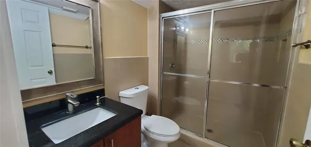 a bathroom with a sink a toilet a shower and a mirror