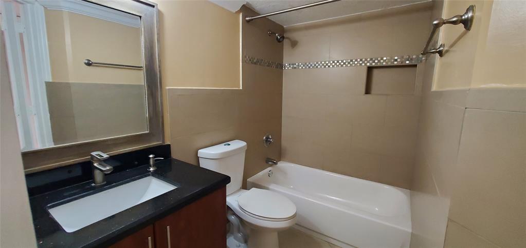 8781 Wiles Road, Unit 202 Coral Springs, FL 33067 - Photo 9 of 20 a bathroom with a granite countertop sink toilet a mirror and shower