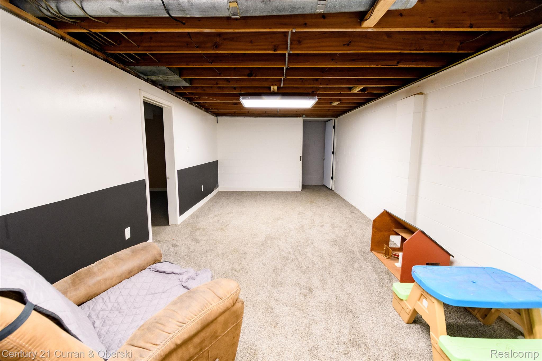 5260 Rives Junction Road Jackson, MI 49201 - Photo 26 of 44 Spacious carpeted room featuring a drop ceiling with exposed joists, white and dark gray painted walls, and overhead fluorescent lighting