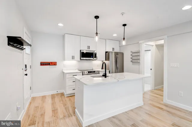 a kitchen that has a lot of white cabinets and wooden floor