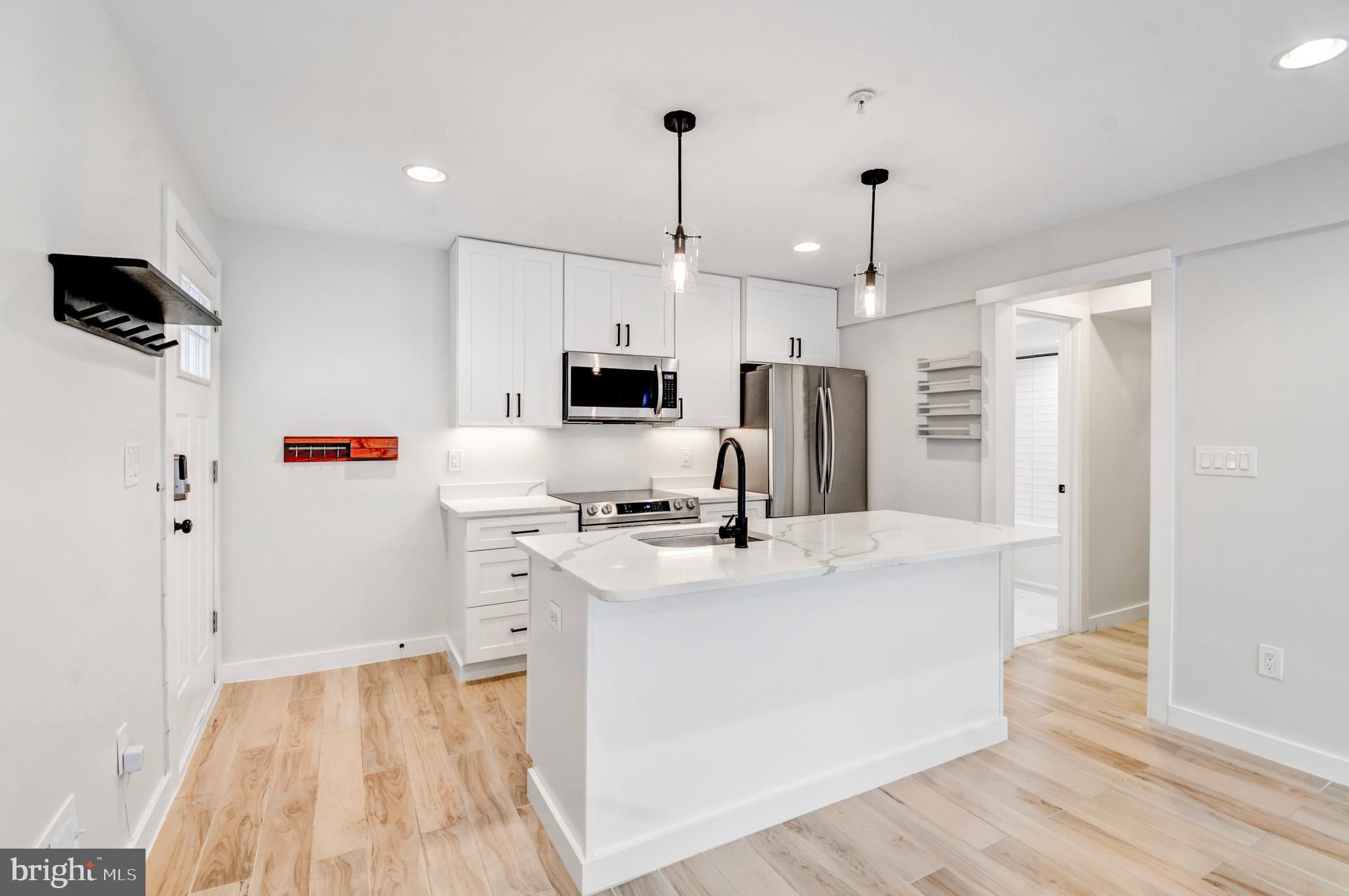 a kitchen that has a lot of white cabinets and wooden floor