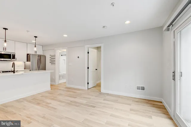 a view of kitchen with stainless steel appliances kitchen island wooden floors and white cabinets