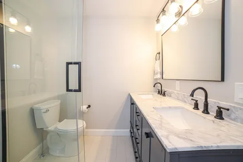 a bathroom with a granite countertop toilet sink and mirror