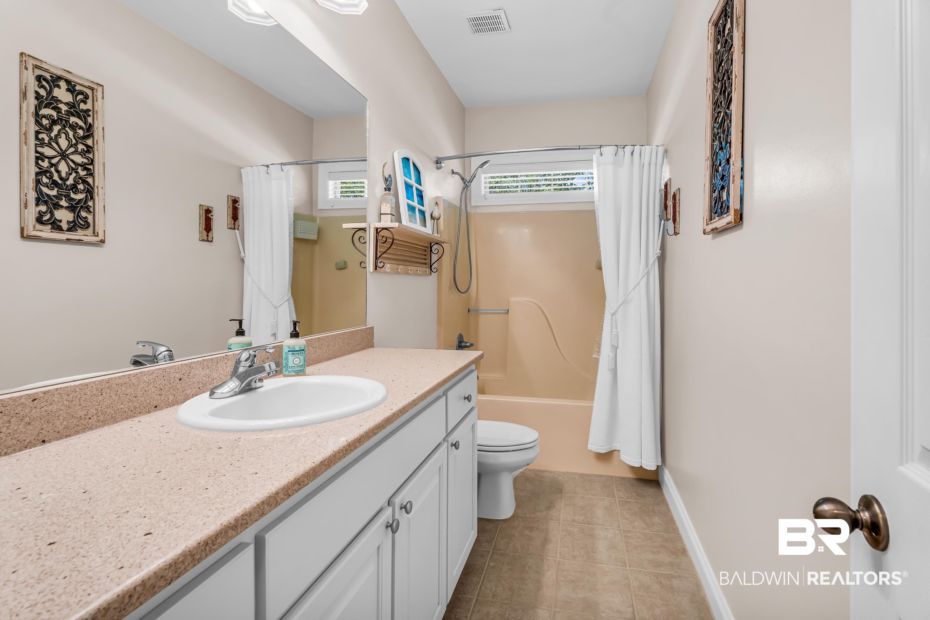 7014 Blakeley Road Daphne, AL 36527 - Photo 32 of 45 Spacious bathroom featuring a full-width mirror, white vanity with ample storage, a speckled countertop, and a shower-tub combination with an overhead window