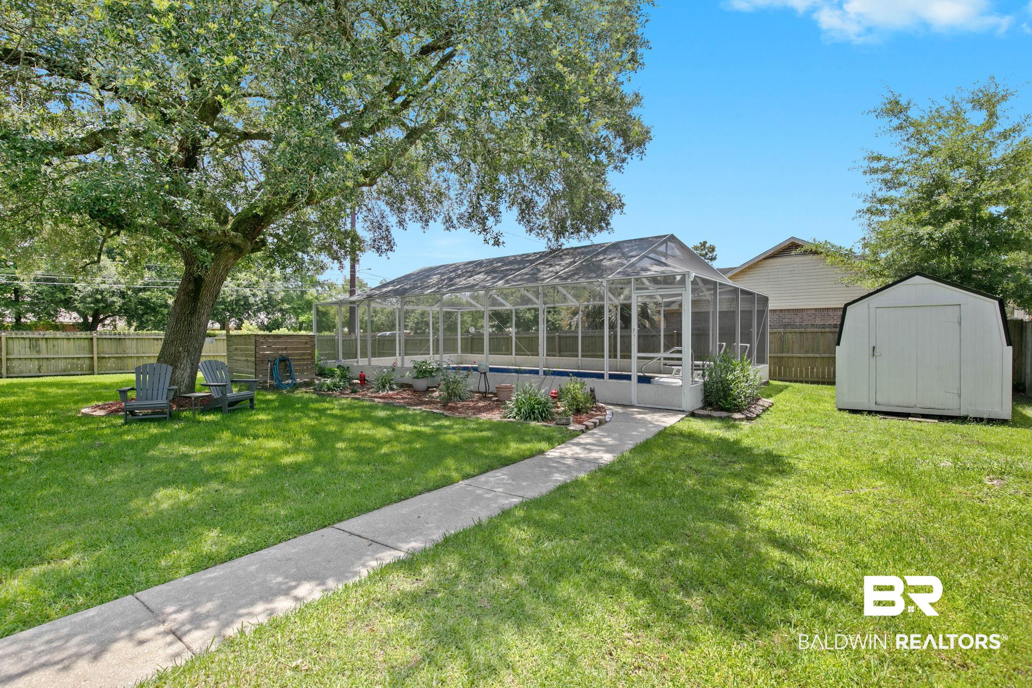 520 Juniper Place Drive Foley, AL 36535 - Photo 33 of 35 Spacious backyard featuring an enclosed swimming pool, mature shade tree, concrete pathway, and a storage shed