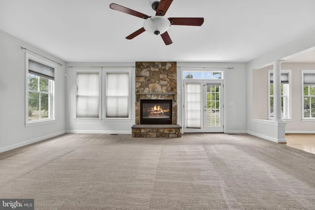 a view of an empty room with window and chandelier fan