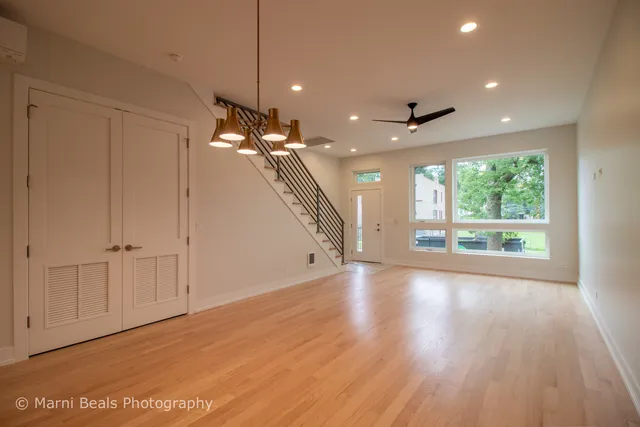 a view of an empty room with wooden floor and a ceiling fan