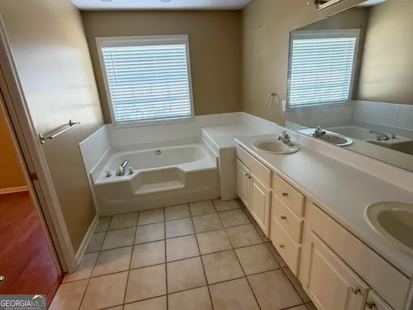 a spacious bathroom with a granite countertop sink a mirror and a bathtub