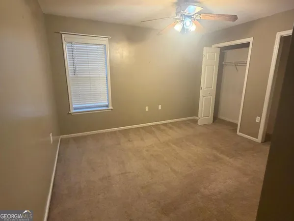 an empty room with chandelier fan and windows