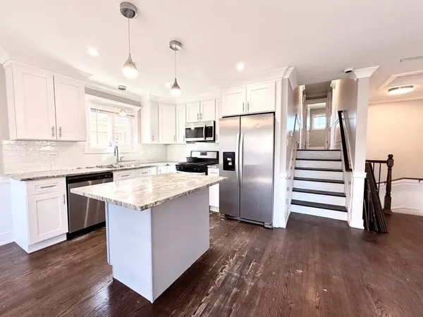 a kitchen with kitchen island wooden floors appliances and cabinets