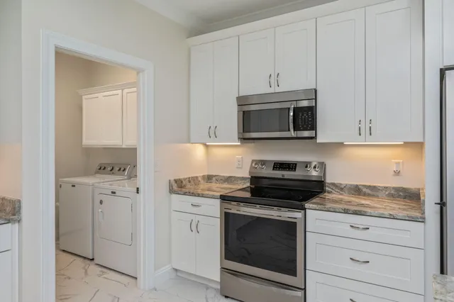 a kitchen with white cabinets and stainless steel appliances