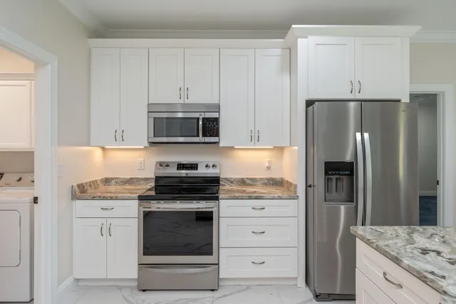 a kitchen with white cabinets and stainless steel appliances