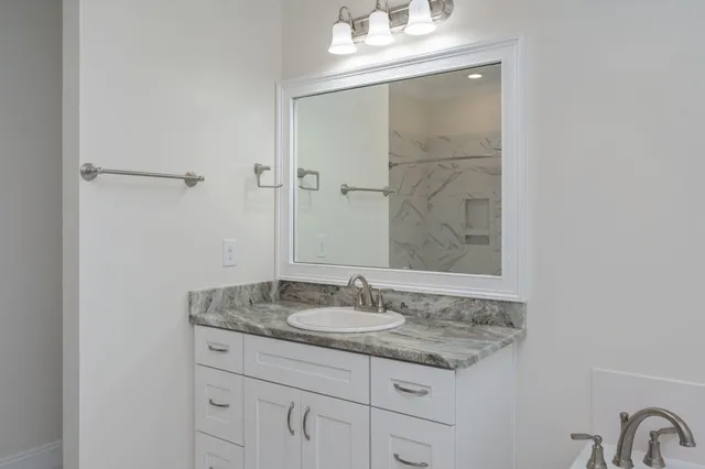 a bathroom with a granite countertop sink and a mirror