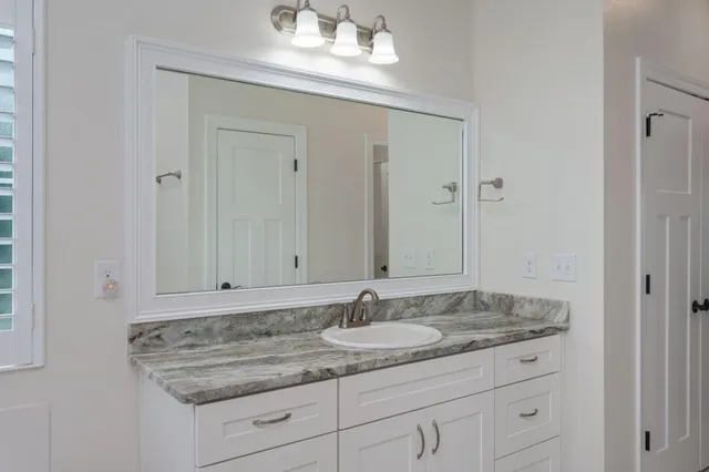 a bathroom with a granite countertop sink and a mirror