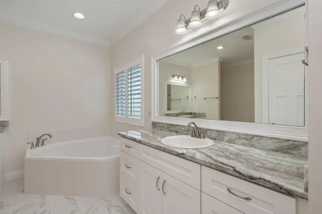 a bathroom with a granite countertop bathtub a double vanity sink and a mirror