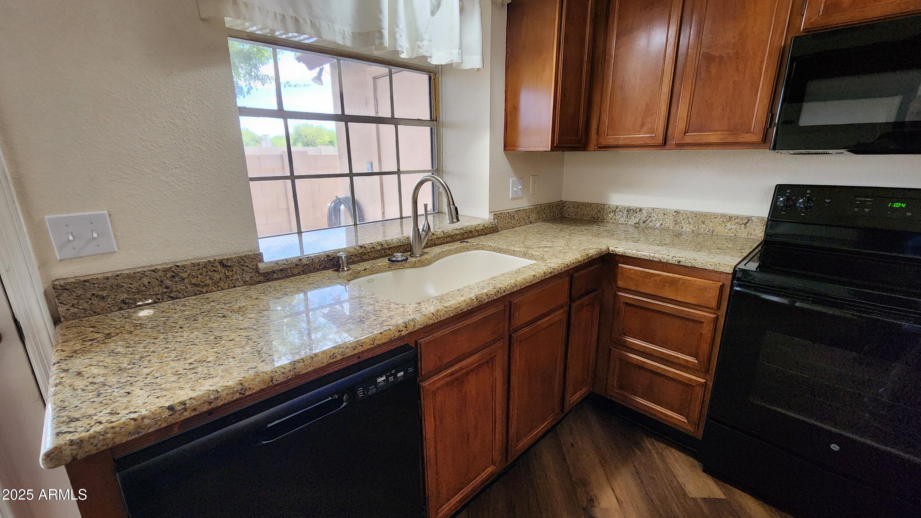 7977 West Wacker Road, Unit 226 Peoria, AZ 85381 - Photo 14 of 19 a kitchen with granite countertop a sink a stove and cabinets