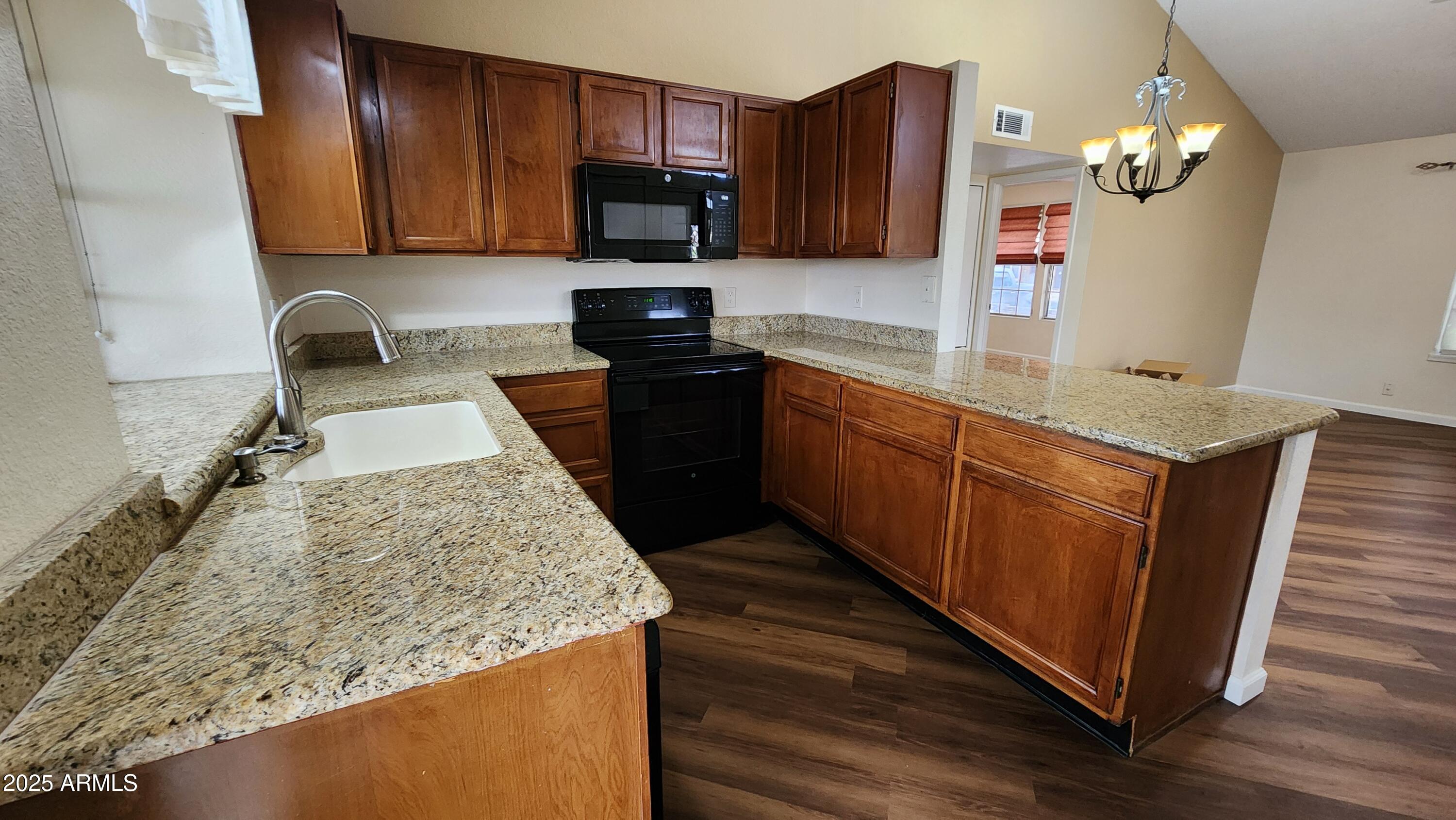 7977 West Wacker Road, Unit 226 Peoria, AZ 85381 - Photo 4 of 19 a kitchen with stainless steel appliances granite countertop wooden cabinets a stove top oven a sink and dishwasher