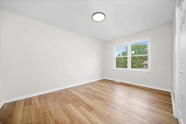 a view of an empty room with window and wooden floor