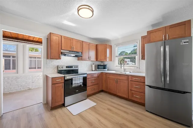 a kitchen with stainless steel appliances granite countertop a refrigerator a stove a sink and a microwave