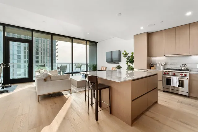a kitchen with kitchen island granite countertop a stove and a view of living room