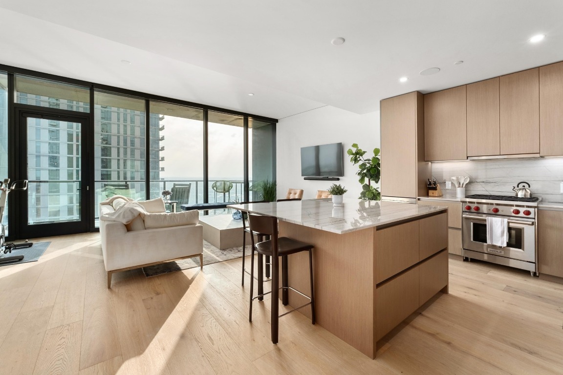 a kitchen with kitchen island granite countertop a stove and a view of living room