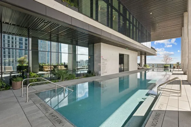 a view of a swimming pool with chairs and floor to ceiling window