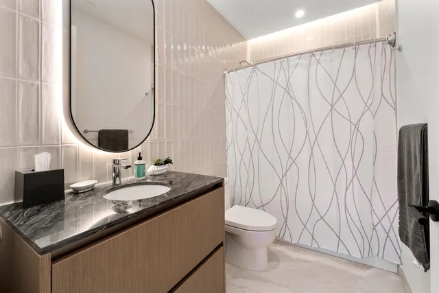 a bathroom with a granite countertop sink and a mirror with toilet