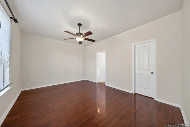 a view of an empty room with wooden floor and a window
