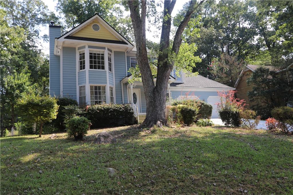 a front view of a house with a yard and trees