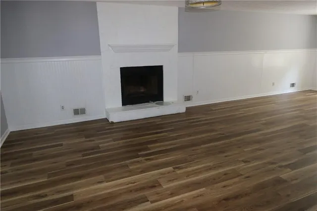 a view of an empty room with wooden floor and a fireplace