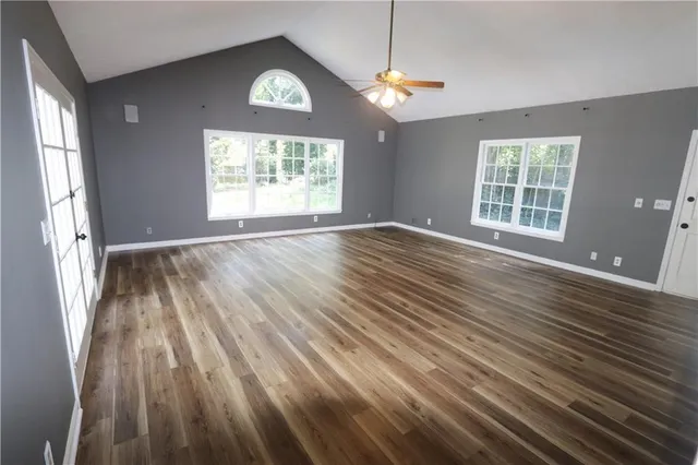 an empty room with wooden floor mirror and windows