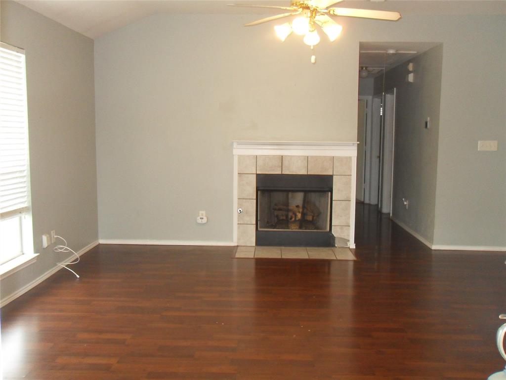 817 Cruise Street Denton, TX 76207 - Photo 2 of 13 an empty room with wooden floor fire place and windows