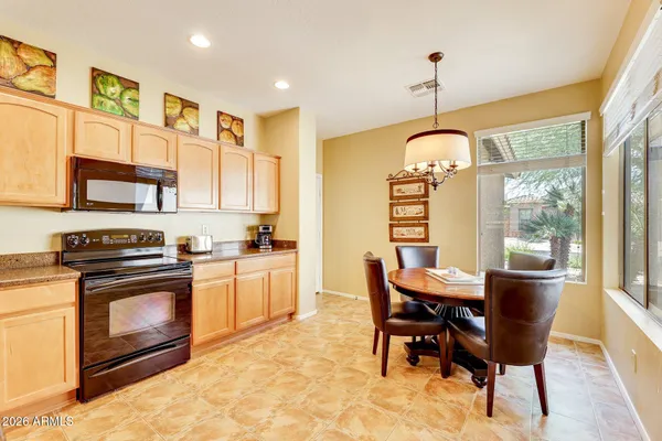 a kitchen with stainless steel appliances granite countertop a stove a sink dishwasher a refrigerator cabinets and a dining table with wooden floor