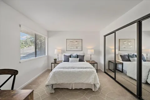 a bedroom with a bed a mirror and a large window