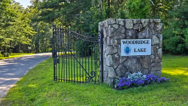 a sign that is sitting in the grass near a house