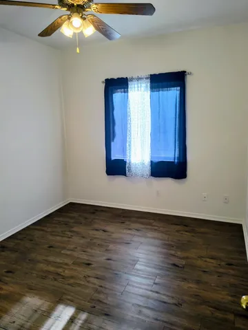 a view of an empty room with wooden floor and a chandelier
